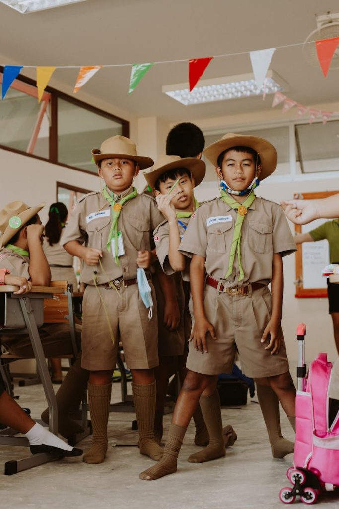 Group of child scouts in uniform posing inside a classroom setting.